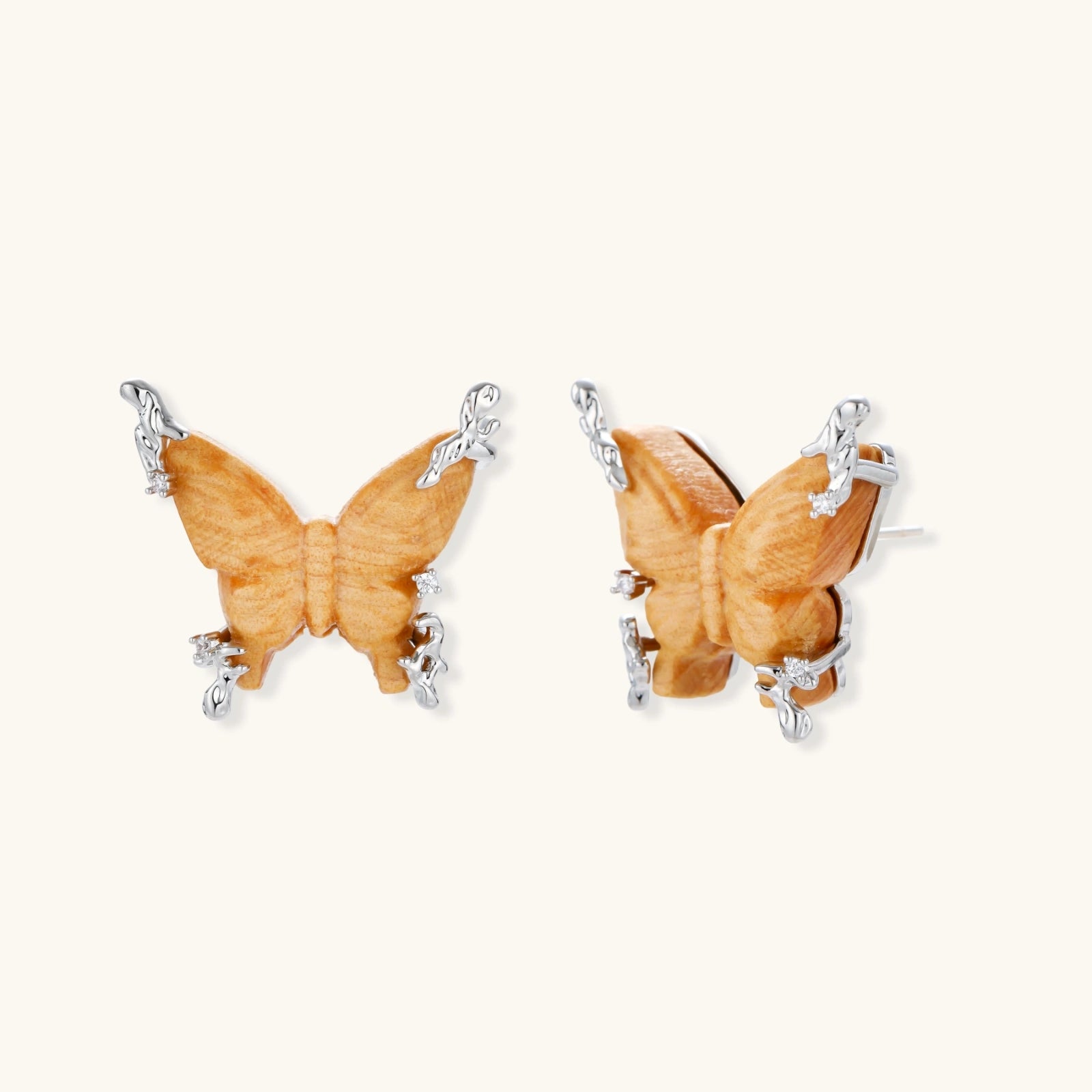 Amber wood butterfly earrings with silver vine details and zirconia accents on cream background