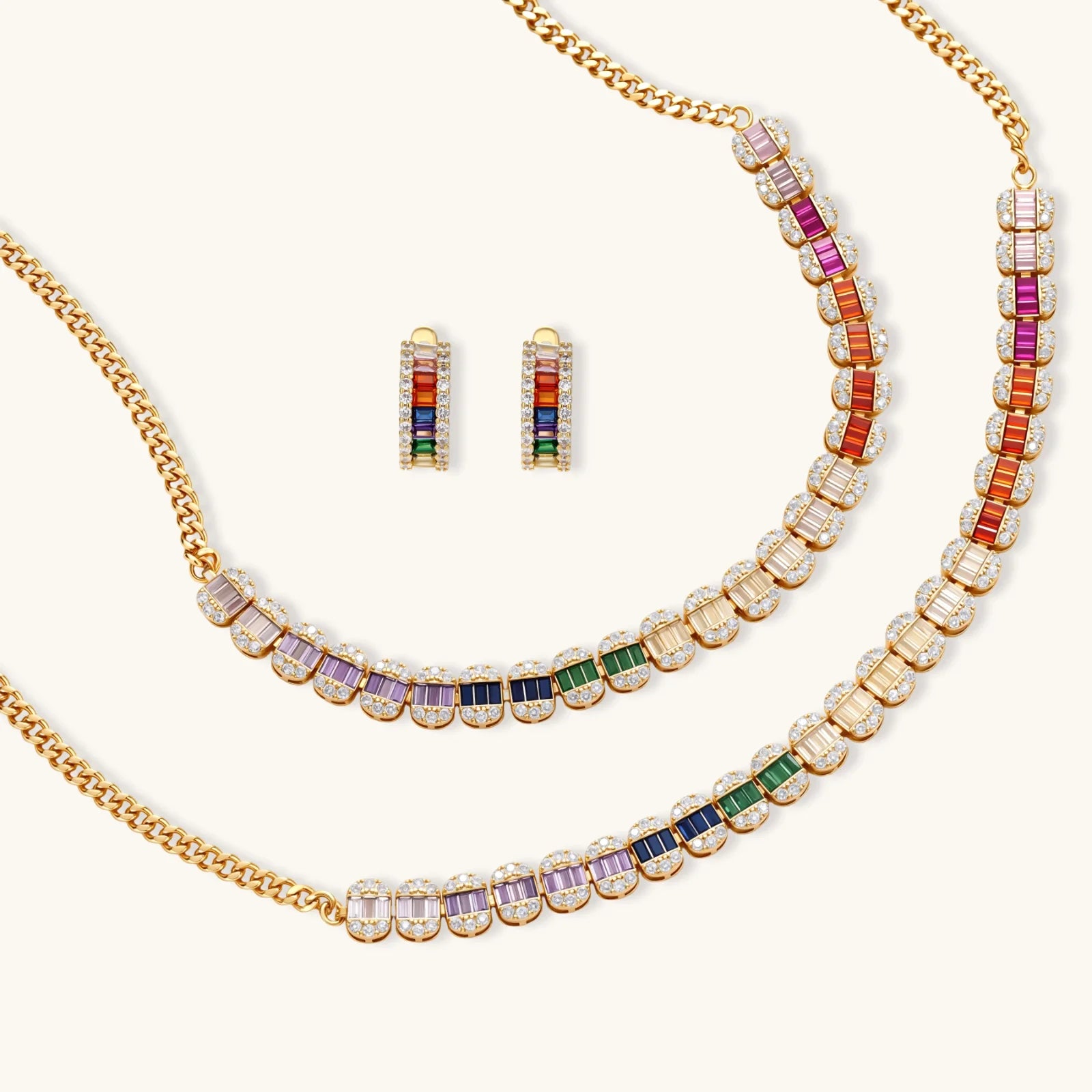 Gold-plated jewelry set featuring rainbow baguette-cut cubic zirconia stones in geometric design on cream background