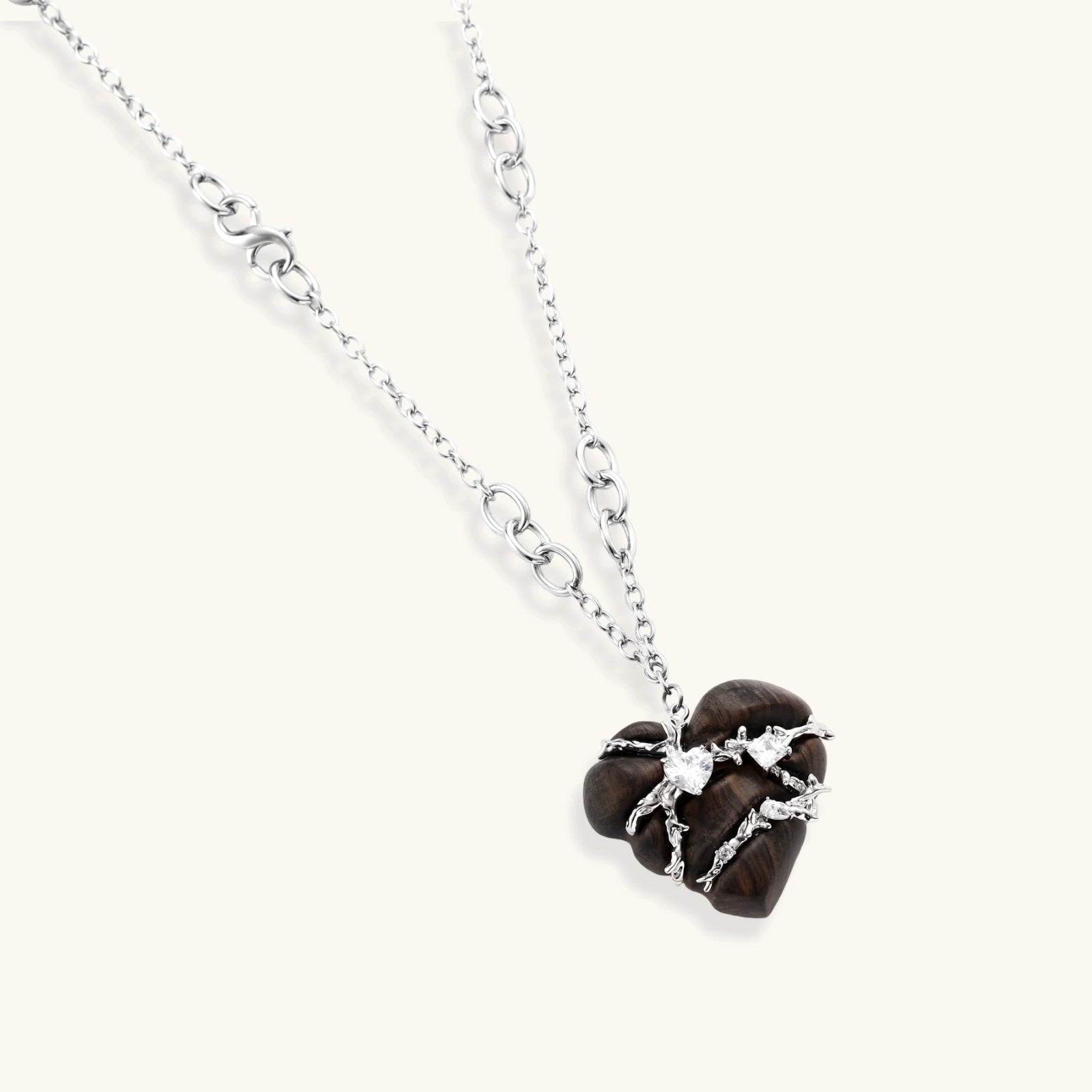 Dark ebony wood heart charms wrapped in intricate silver chains with crystal accents, shown as matching earrings and necklace set.