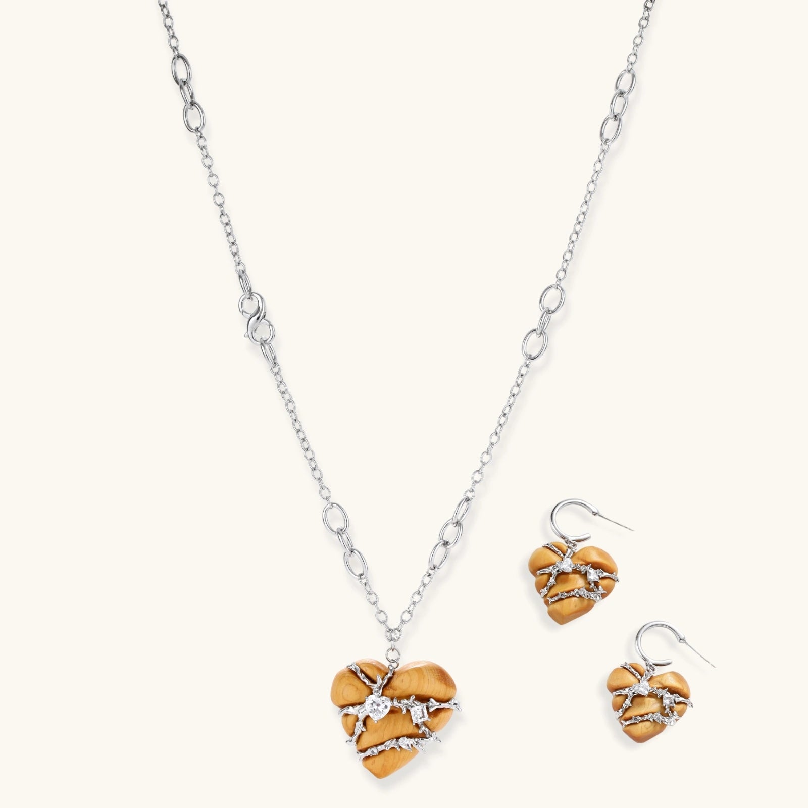 Heart-shaped eco-brass and wood jewelry set with silver wire detailing and crystal accents on cream background.