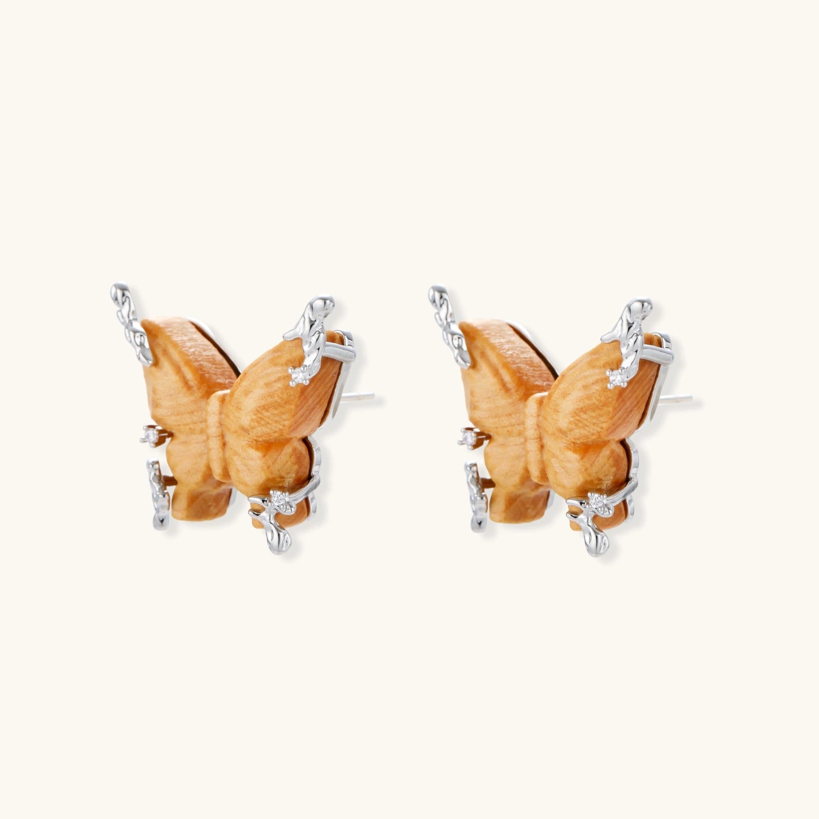 Amber wood butterfly earrings with silver vine details and zirconia accents on cream background