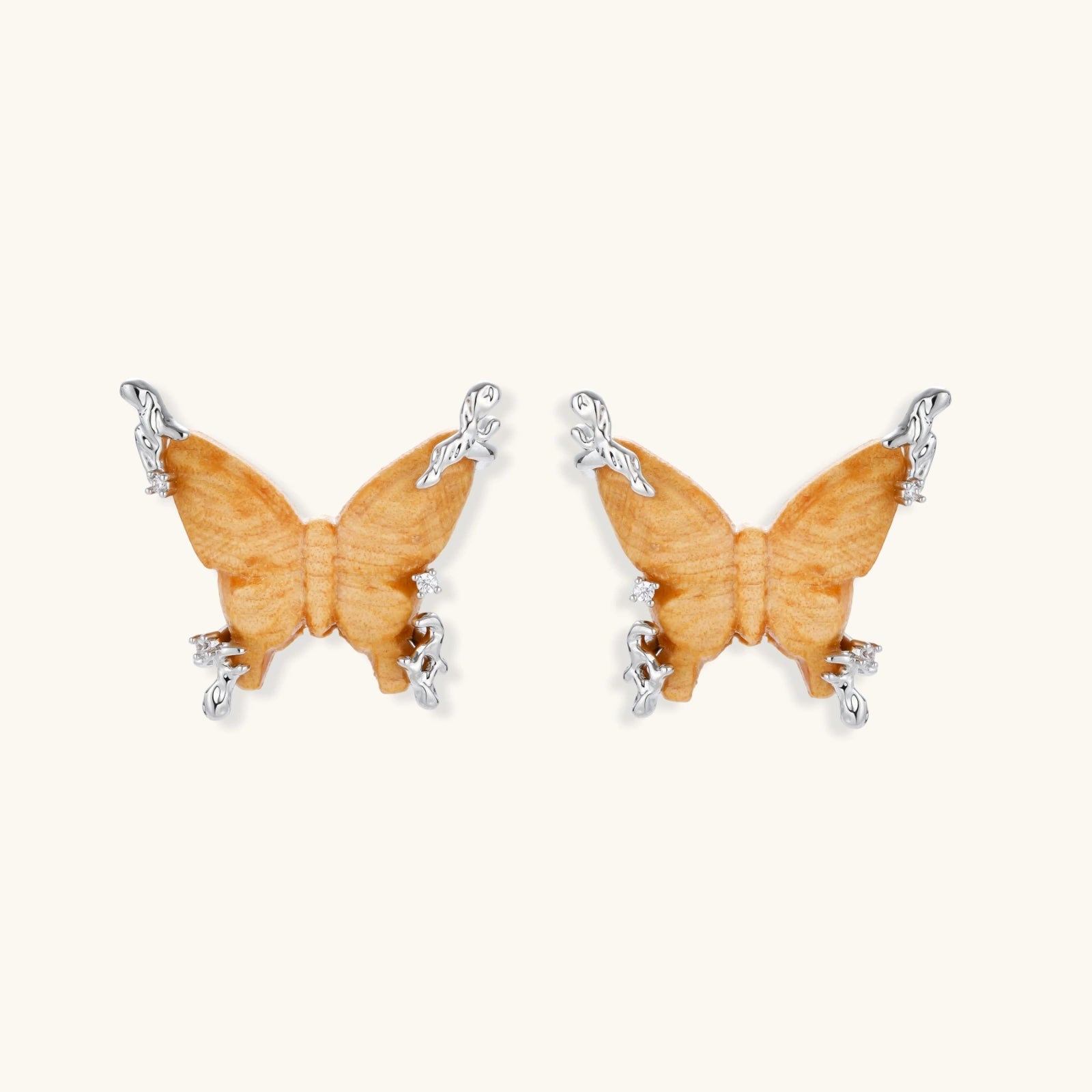 Amber wood butterfly earrings with silver vine details and zirconia accents on cream background